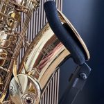 Close-up of a gold brass saxophone showing keys and curved tubing on a wooden surface with a dark background