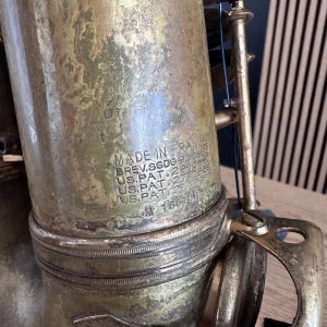 Close-up of a worn metal surface with engraved text, including 'MADE IN FRANCE' and 'US PAT' markings, showing corrosion and a threaded base.