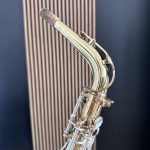Close-up of a vintage chrome microphone arm with a speckled capsule against a dark blue backdrop.