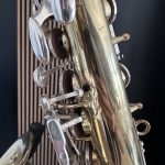 Close-up of shiny metal gears and brackets on a cylindrical frame, with circular openings and a dark background.