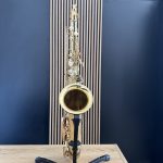 Shiny gold saxophone on a stand in a music studio with blue walls.