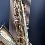 Close-up of a shiny brass saxophone showing its intricate keywork against a dark background.